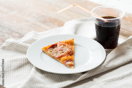 Slice of pizza with cola soda on table