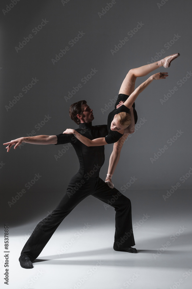 Naklejka premium two young modern ballet dancers on gray studio background 