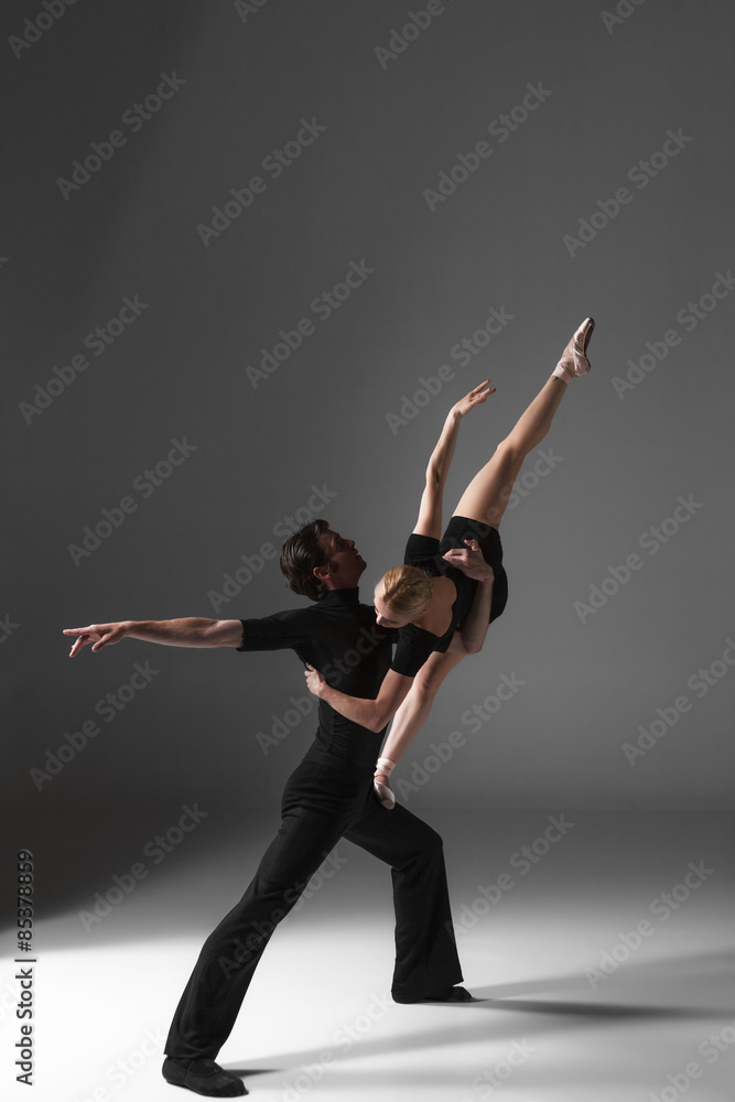 Obraz premium two young modern ballet dancers on gray studio background