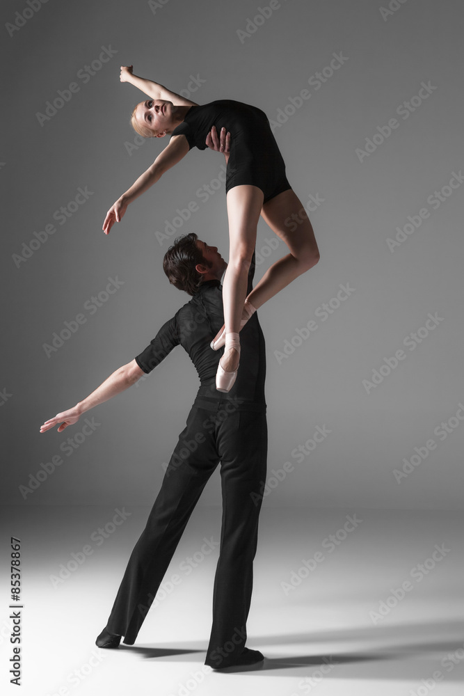 Obraz premium two young modern ballet dancers on gray studio background
