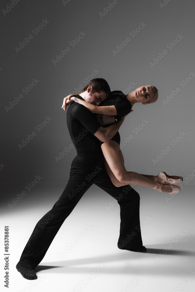 Obraz premium two young modern ballet dancers on gray studio background