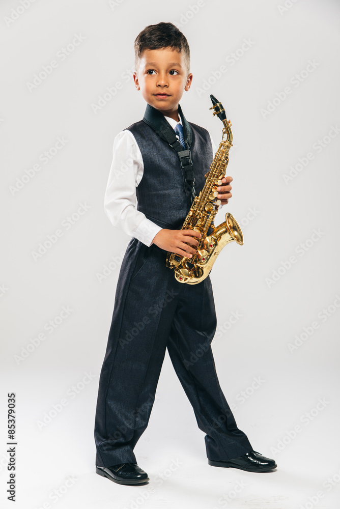 Fototapeta premium six years old boy plays saxophone at studio