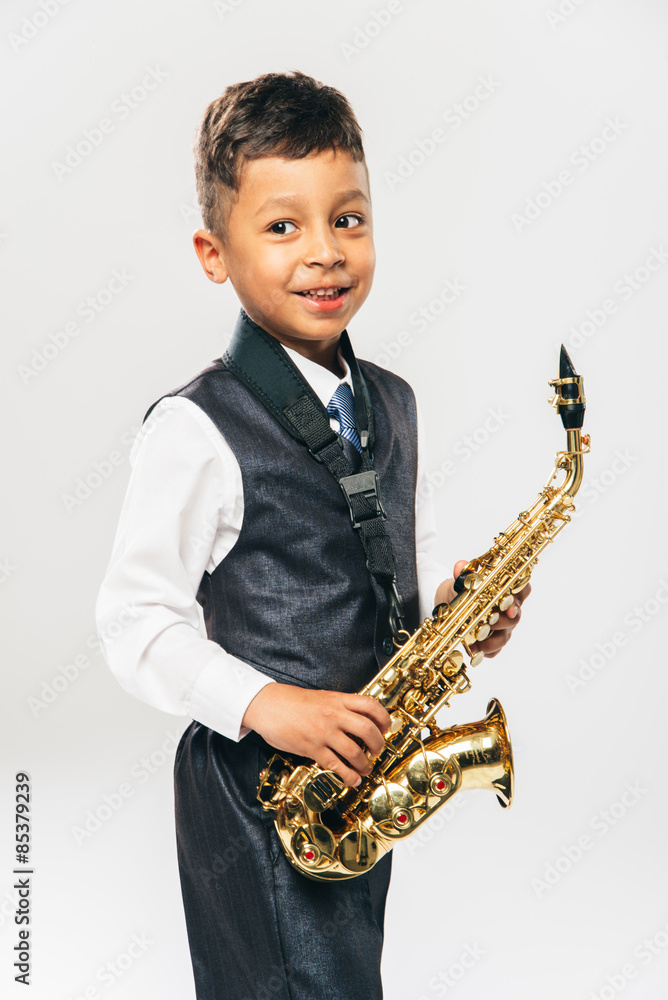 Fototapeta premium six years old boy plays saxophone at studio