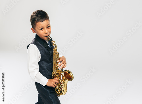 six years old boy plays saxophone at studio
