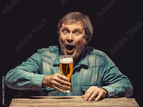 The screaming man in denim shirt with glass of beer