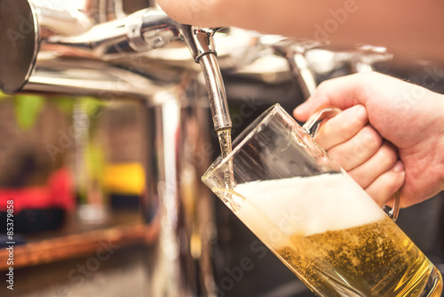 bistro waiter serving a cold  chill beer. Hand of barman pouring a lager beer from tap