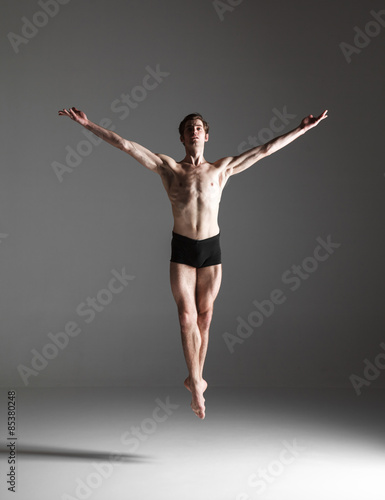 The young attractive modern ballet dancer jumping on white