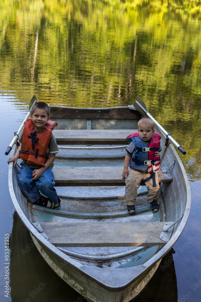 Obraz premium Two young boys sitting in a rowboat on the water.