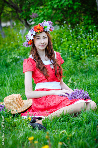 beautiful woman sitting in a wreath on a meadow © timonko