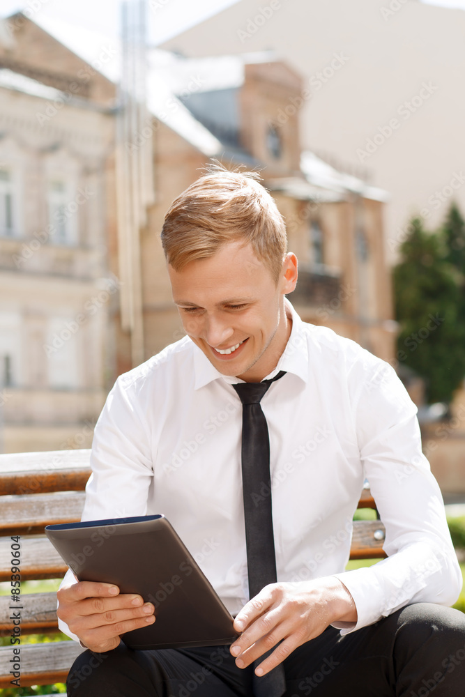 Smiling man using tablet outside Smiling man using tablet outside