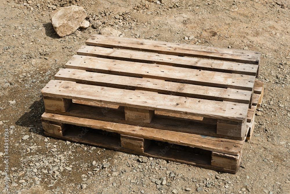Zwei Paletten aus Holz liegen auf einer Schotterfläche