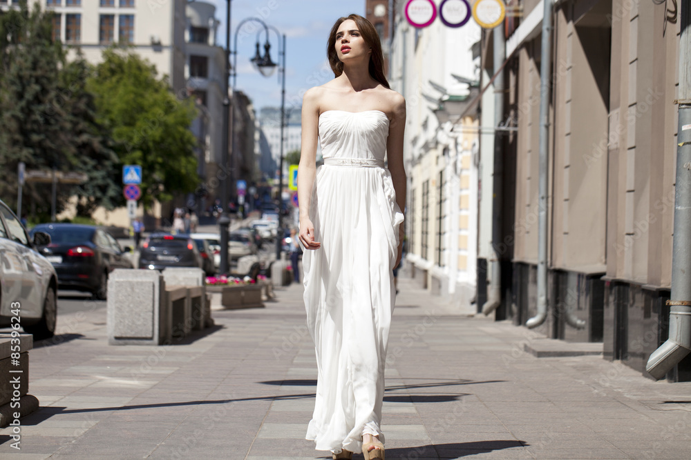 Full length portrait of beautiful model woman walking in white d