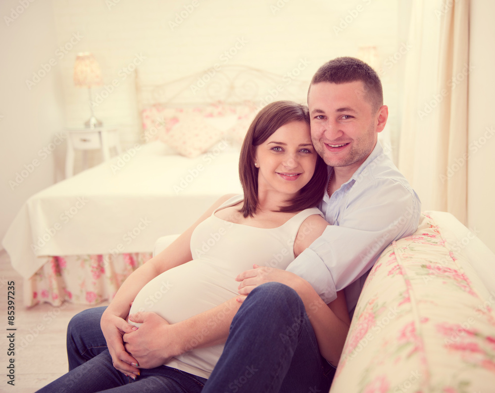 Happy pregnant couple on sofa