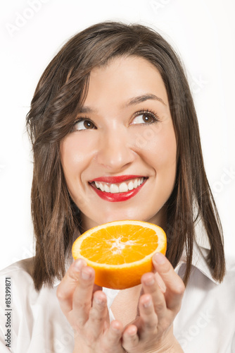 Happy woman holding orange slice in hands looking aside, studio shot on white