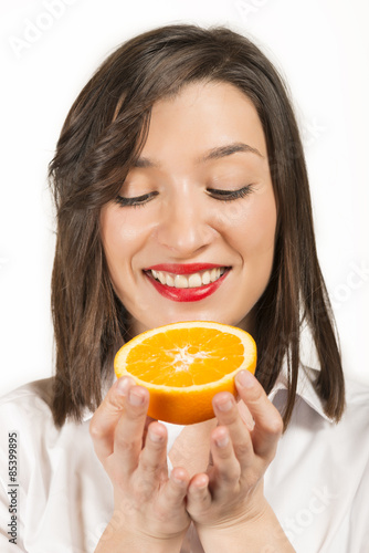 Happy woman holding orange slice in hands looking at it, studio shot on white