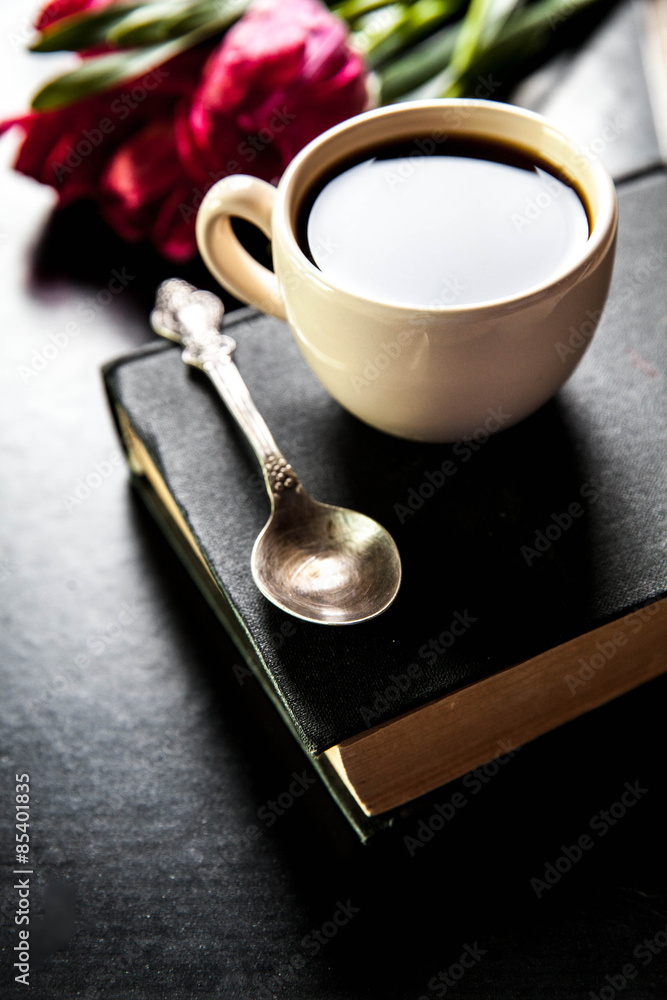 cup of coffee with tulip and book on black background cup of coffee with tulip and book on black background