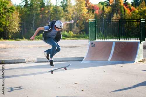 teen boy skateboarding at the local skate park on a beautiful fall evening photo