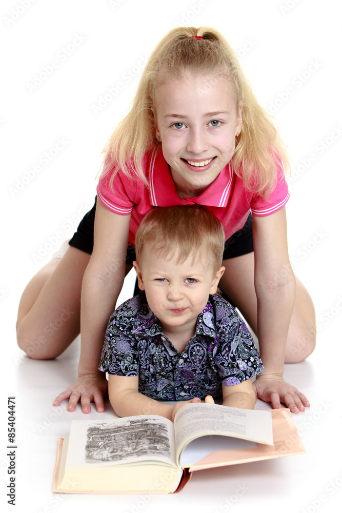 Big sister and little brother reading a book lying on the floor Big sister and little brother reading a book lying on the floor