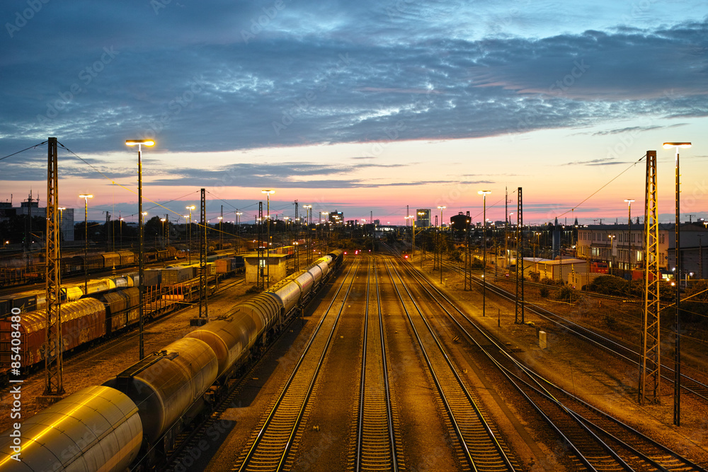 Naklejka premium Sonnenuntergang am Rangierbahnhof mit Zügen, Waggons, Gütern