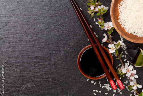 фотографія Japanese sushi chopsticks, soy sauce bowl, rice and sakura bloss