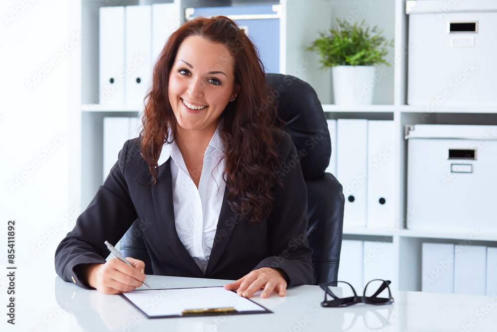 Businesswoman sitting behind the desk in the office Businesswoman sitting behind the desk in the office
