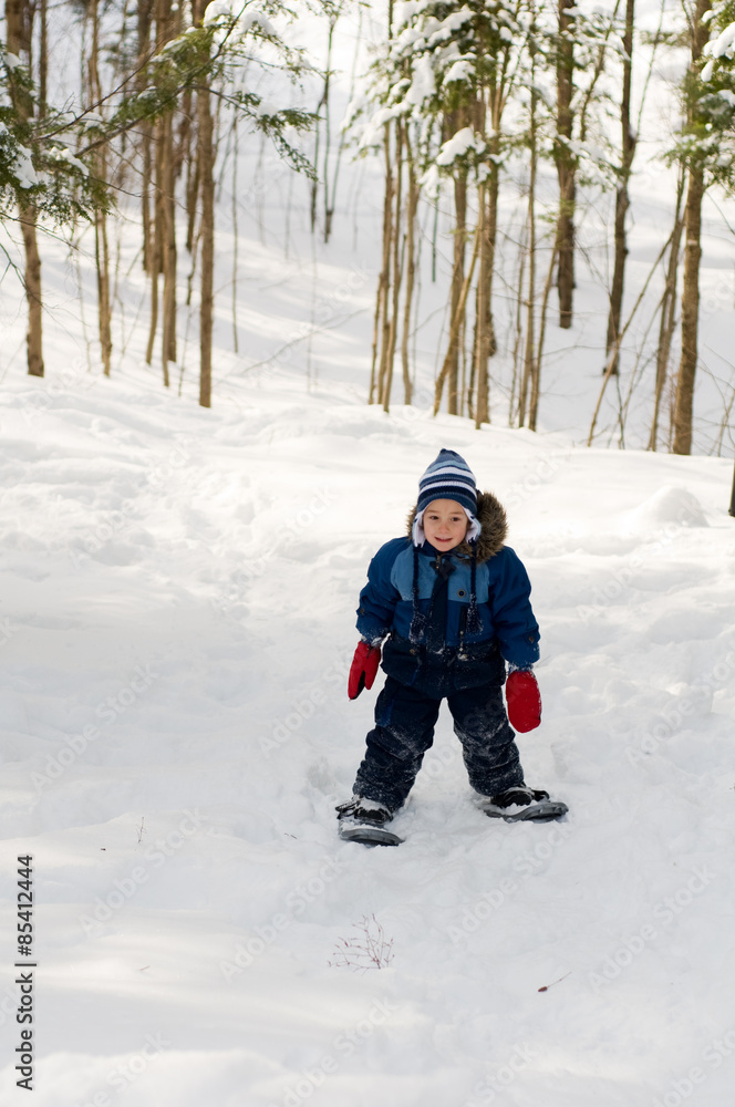 four year old boy out snowshoeing in a winter forest