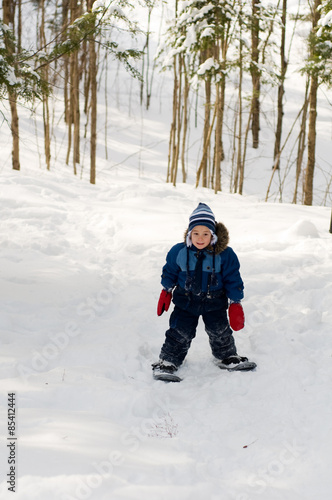 four year old boy out snowshoeing in a winter forest
