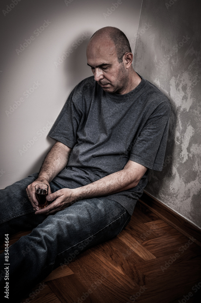 Drunk man sitting on the floor, sleeping and holding a glass of alcohol drink Drunk man sitting on the floor, sleeping and holding a glass of alcohol drink