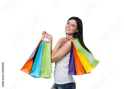 A happy brunette woman with the colourful shopping bags from the fancy shops. Isolated.