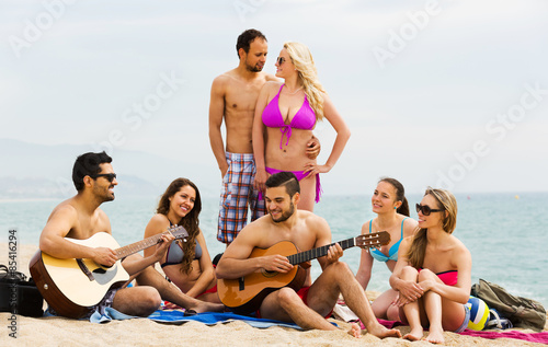 Friends with guitar at beach . © JackF