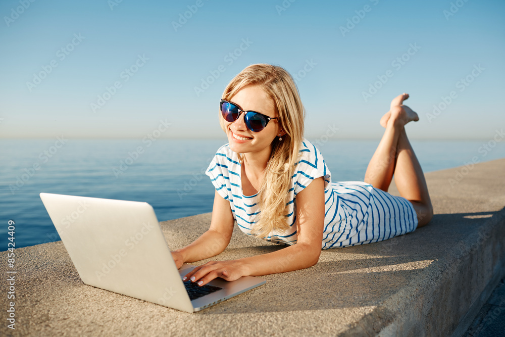 Cheerful girl lying on the beach and talks to her friends