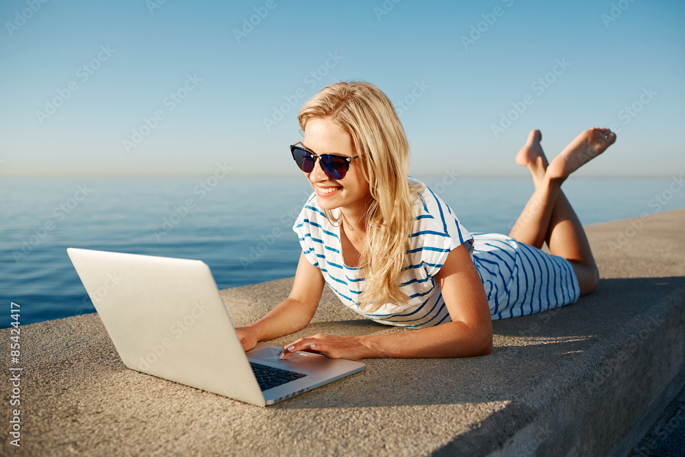 Cheerful girl lying at summer on the beach near sea and talks