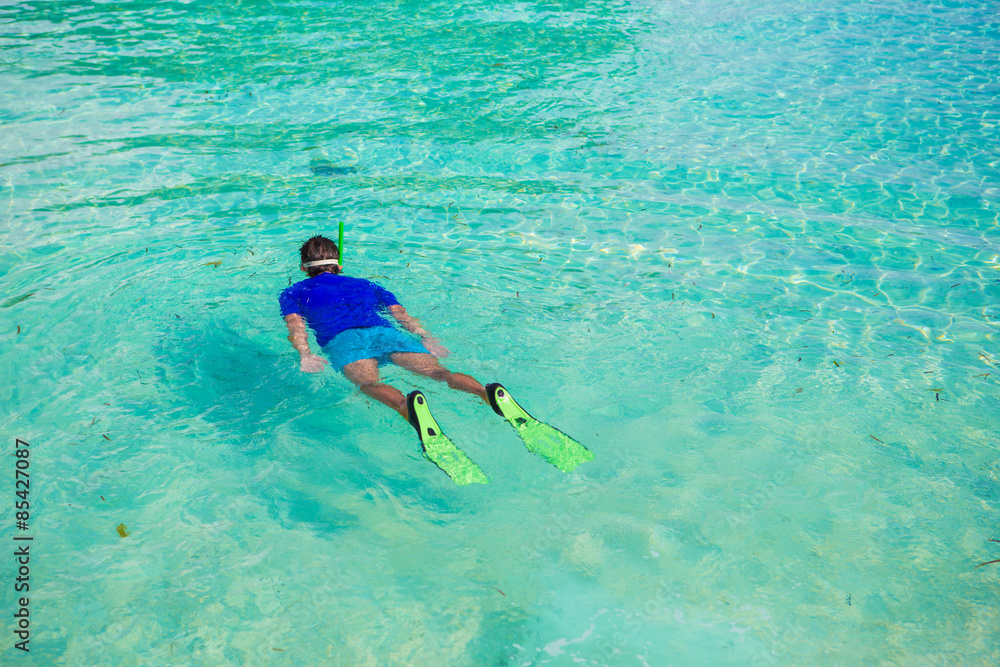 Young boy snorkeling in tropical turquoise ocean