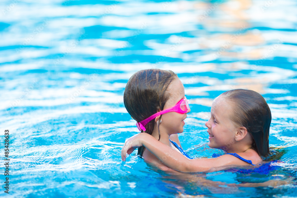 Adorable little girls playing in outdoor swimming pool
