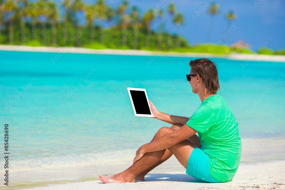Young man working with laptop at tropical beach