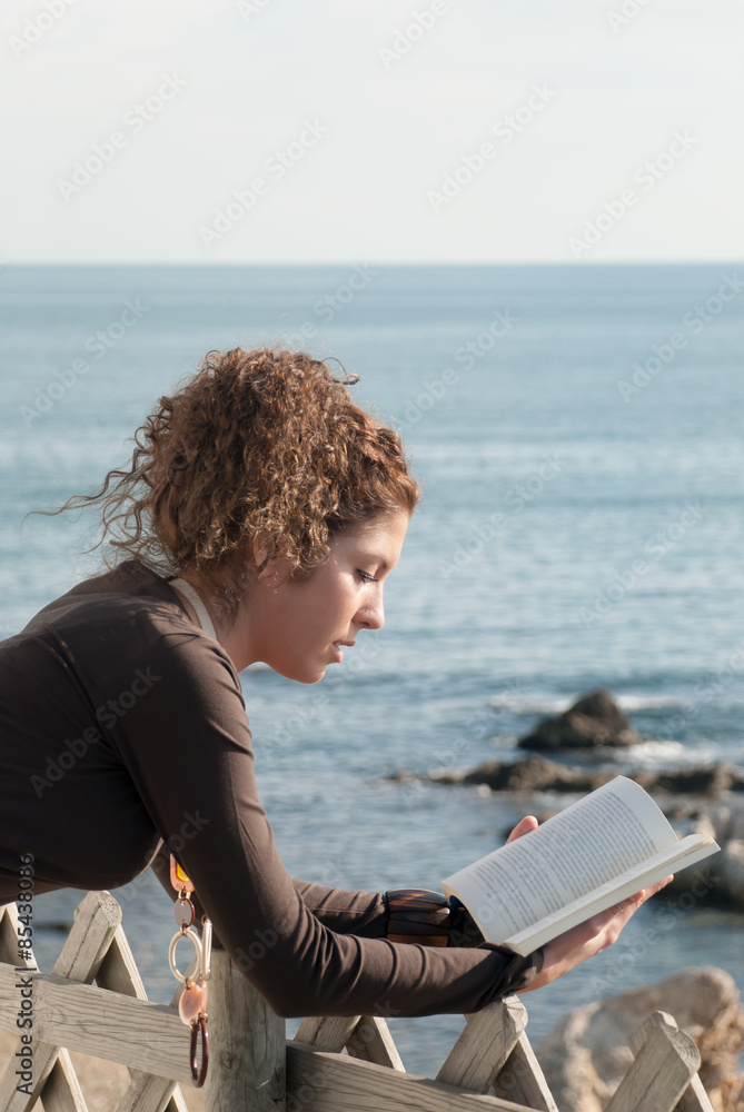 lady reading a book near the sea