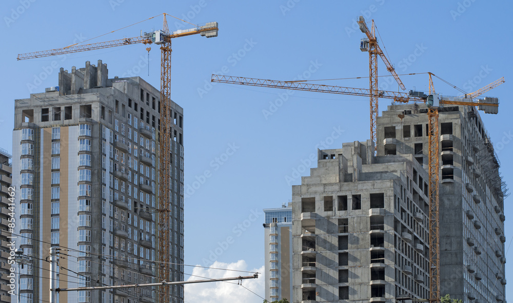 Three high-rise buildings and cranes against the sky Three high-rise buildings and cranes against the sky