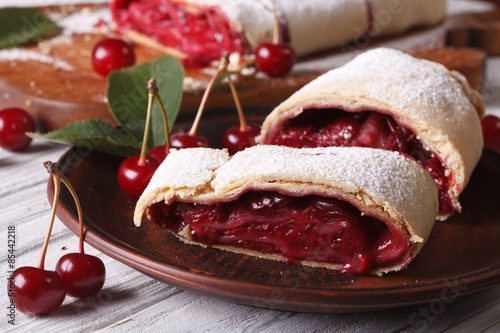 Photos Sliced strudel with cherry close-up on a plate. horizontal