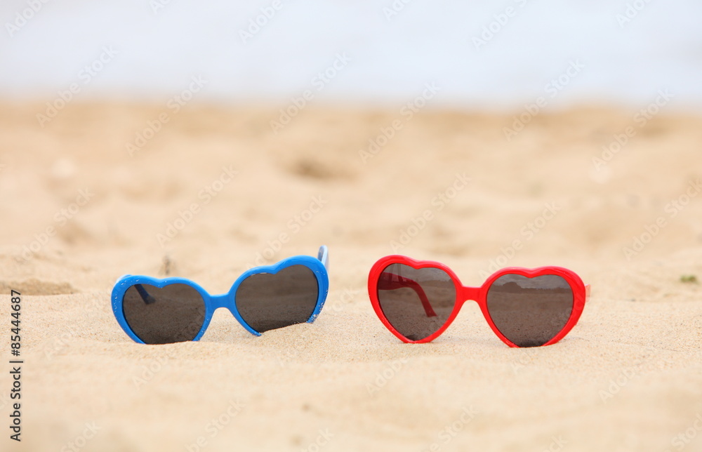 Colorful sunglasses shaped heart on the sand