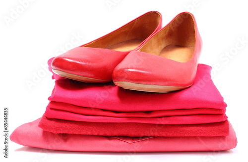 Womanly shoes and pile of red clothes. White background