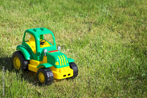 Toy green-yellow tractor on the green grass.