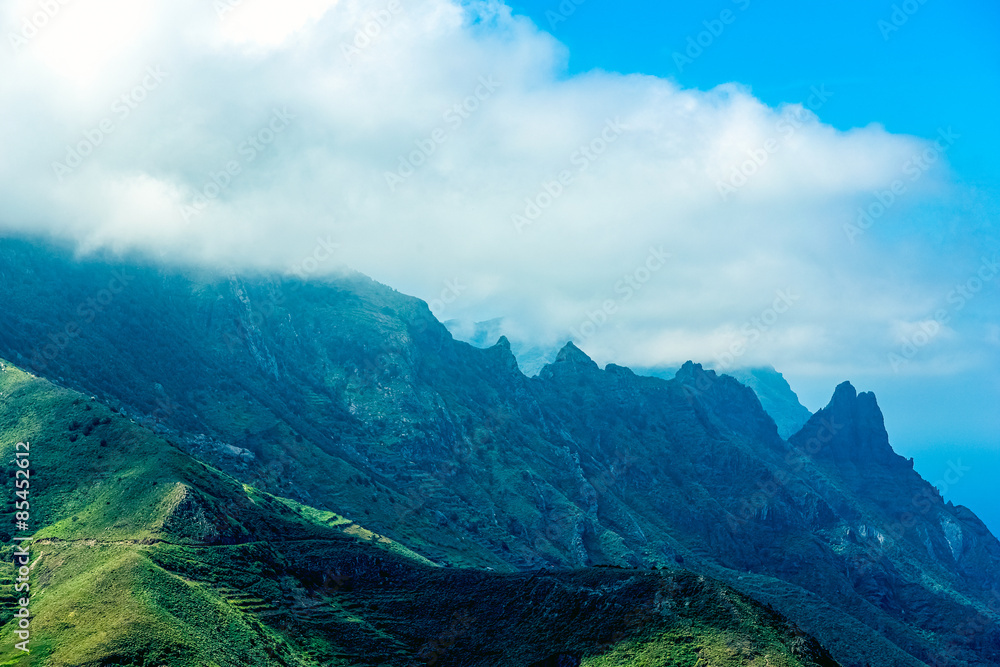 Naklejka premium Green rocks with clouds on blue sky