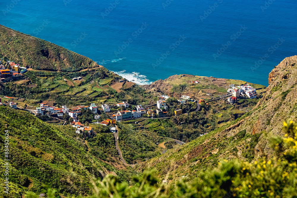 Village in green valley near ocean