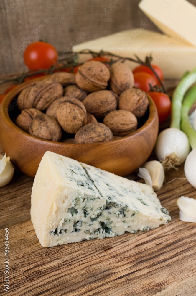 Big portion of niva cheese in front of various vegetable Big portion of niva cheese in front of various vegetable
