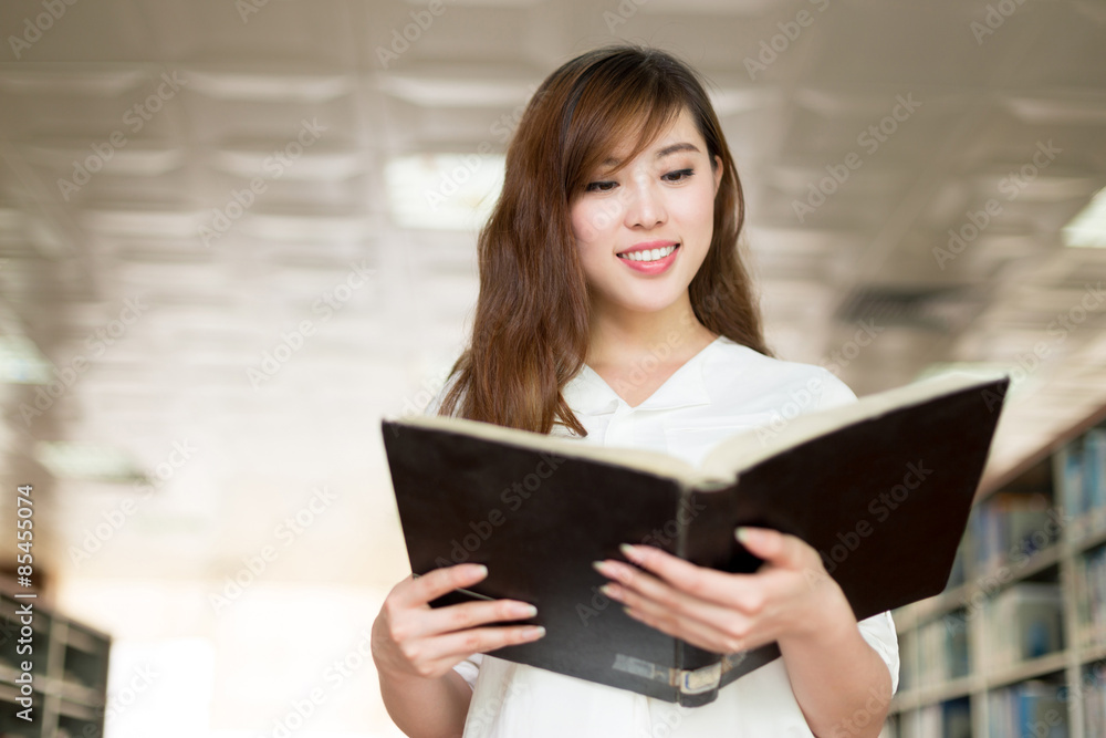 Asian beautiful female student holding book in library Asian beautiful female student holding book in library