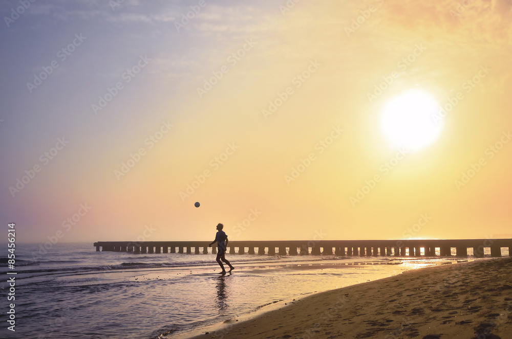 Fototapeta premium Footballer is playing on the morning Beach