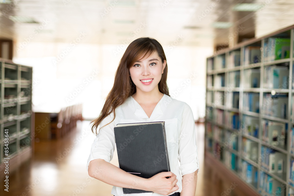 Asian beautiful female student holding book in library Asian beautiful female student holding book in library
