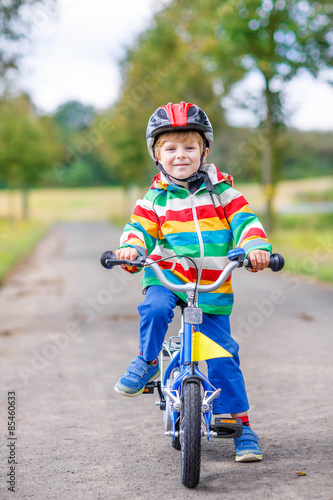 Fototapeta Naklejka Na Ścianę i Meble -  Happy adorable kid boy in safety helmet on bike