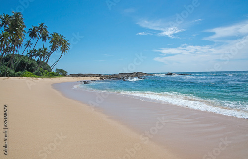 Paradise beach with green turquoise waves, coconut palm trees and fine untouched sand, Southern Province, Sri Lanka, Asia.