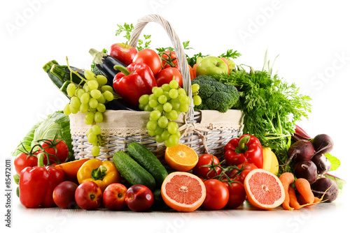 Organic vegetables and fruits in wicker basket isolated on white